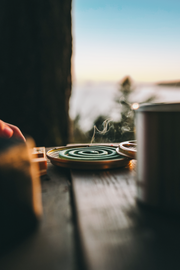 Close up of a green mosquito coil sitting on a picnic bench with wisps of smoke being emitted.