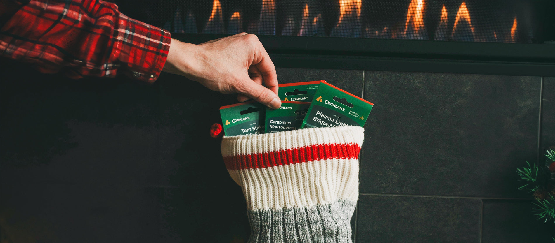 Close-up of person wearing red plaid pajamas reaching into a stocking to pull out a set of carabiners