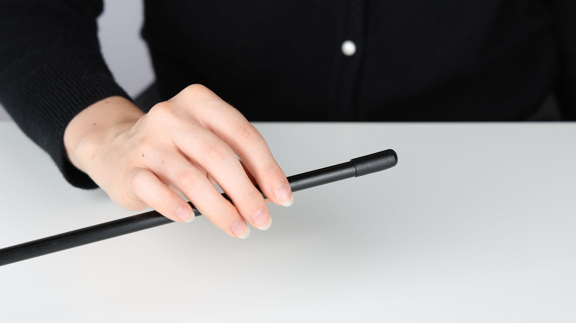 A hand holding a Coghlan's replacement tent pole with a black  plastic end cap