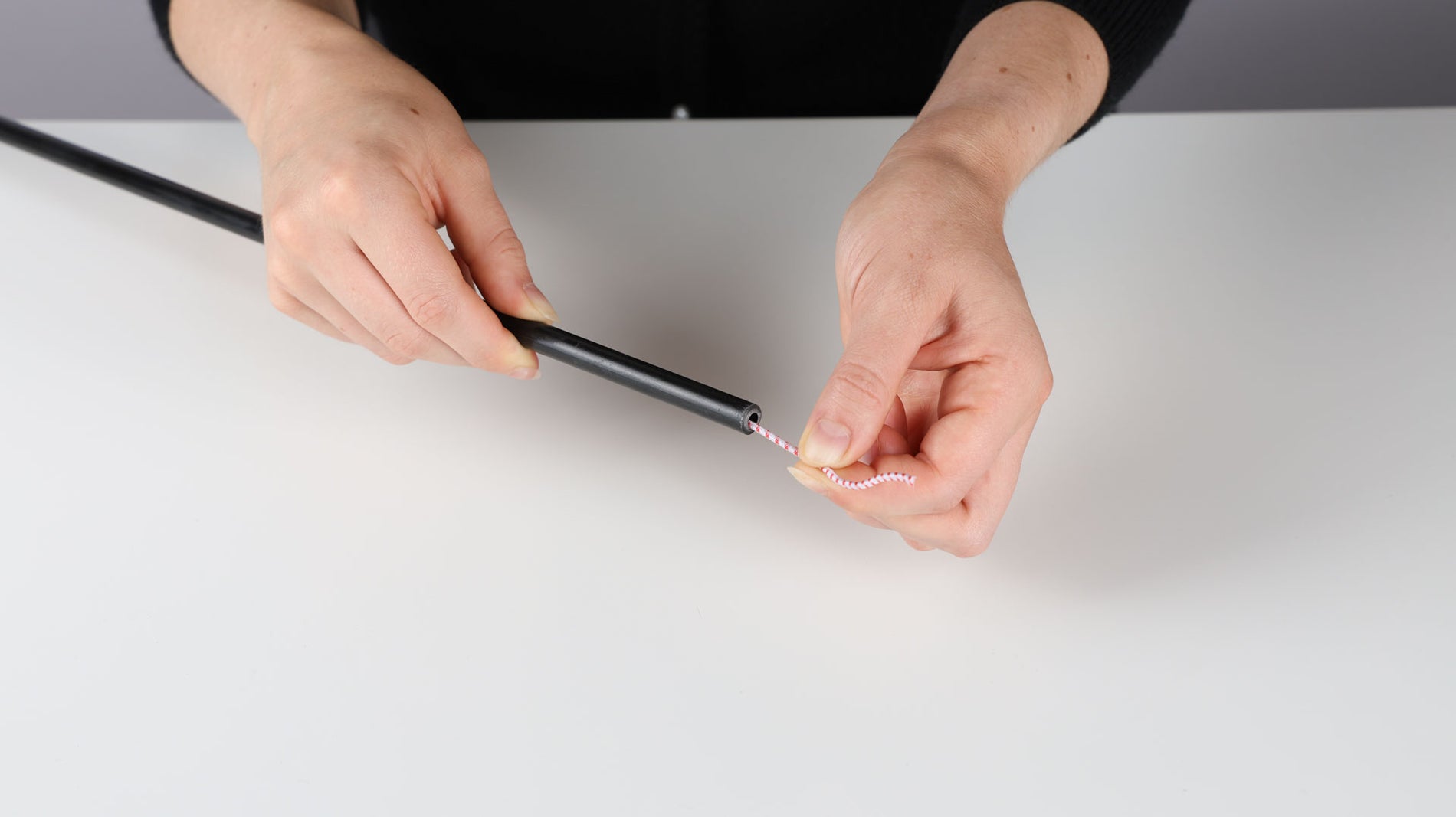 Hands showing the same tent pole with the shock cord untied or knot removed