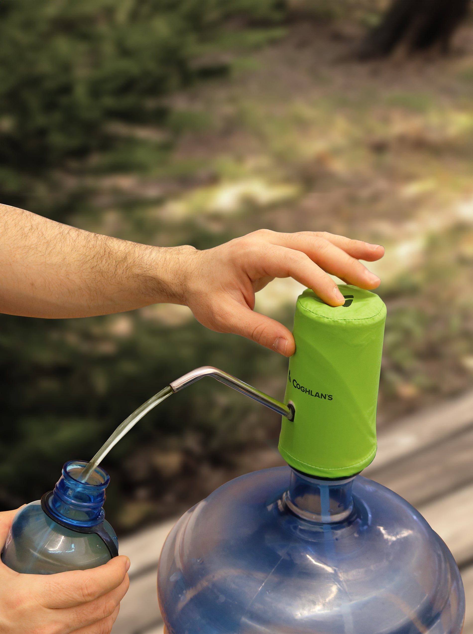 Close up of hands using a water pump attached to a water container to fill a water bottle