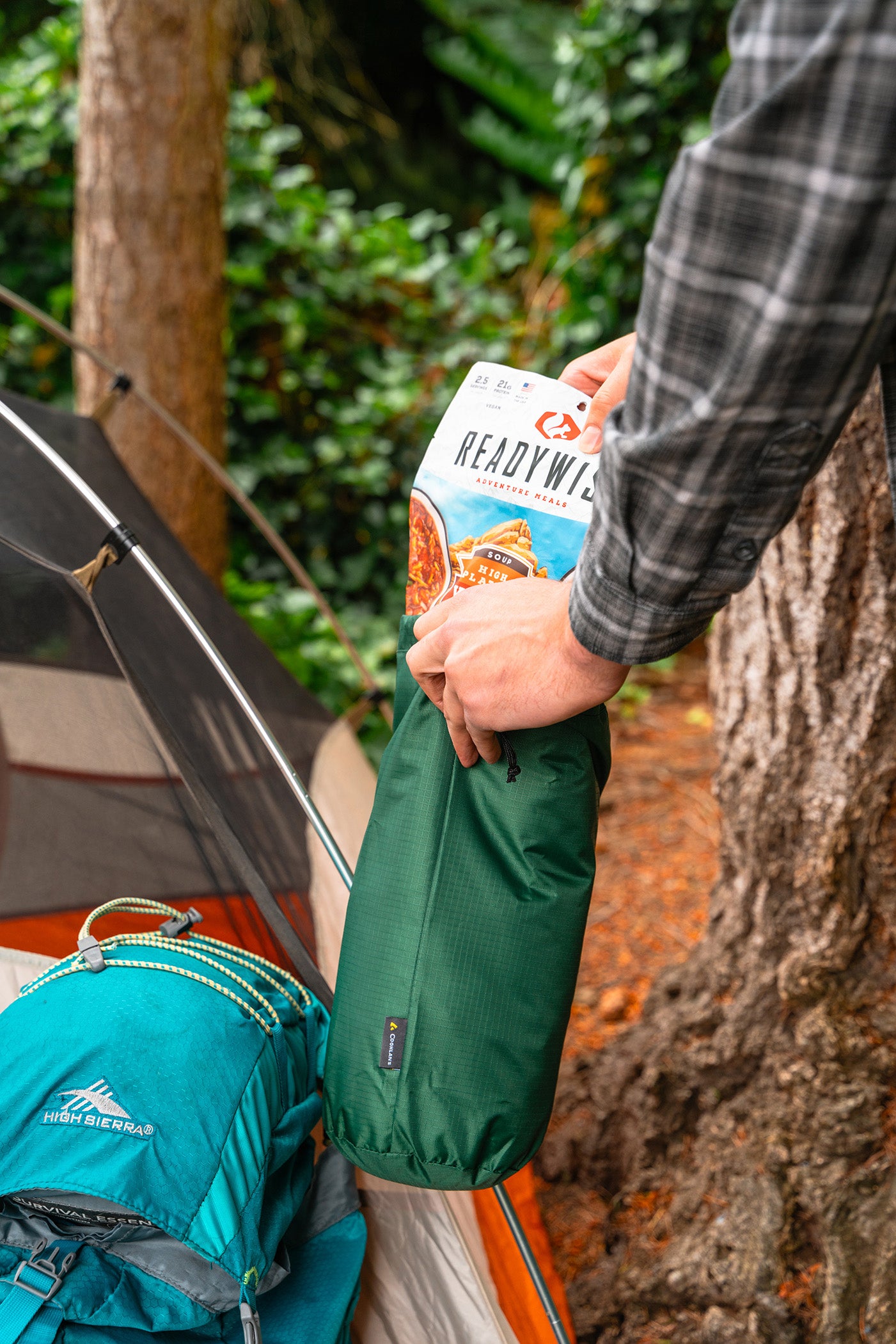 Dehydrated backpacking meal being packed into a green stuff sack at a campsite