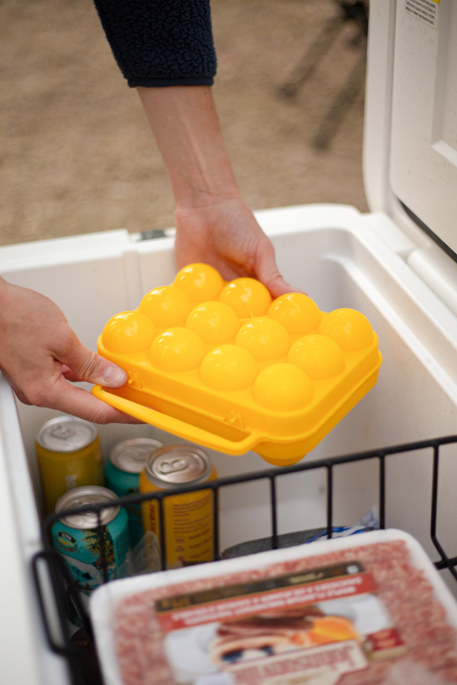 Hands reaching for an Egg Holder out of a cooler.