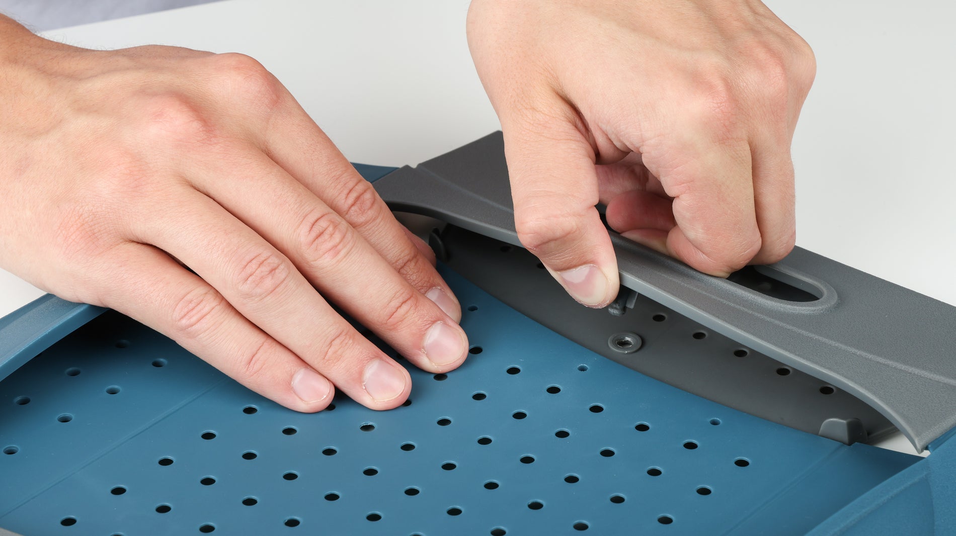 Hand lifting the folded handle to unlock the snap faster of the Coghlans Snapfold Colander