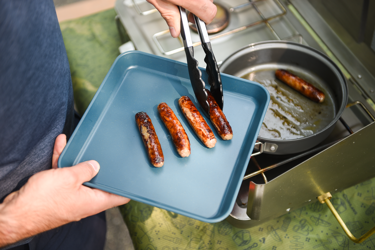 Adding cooked sausages to a plate